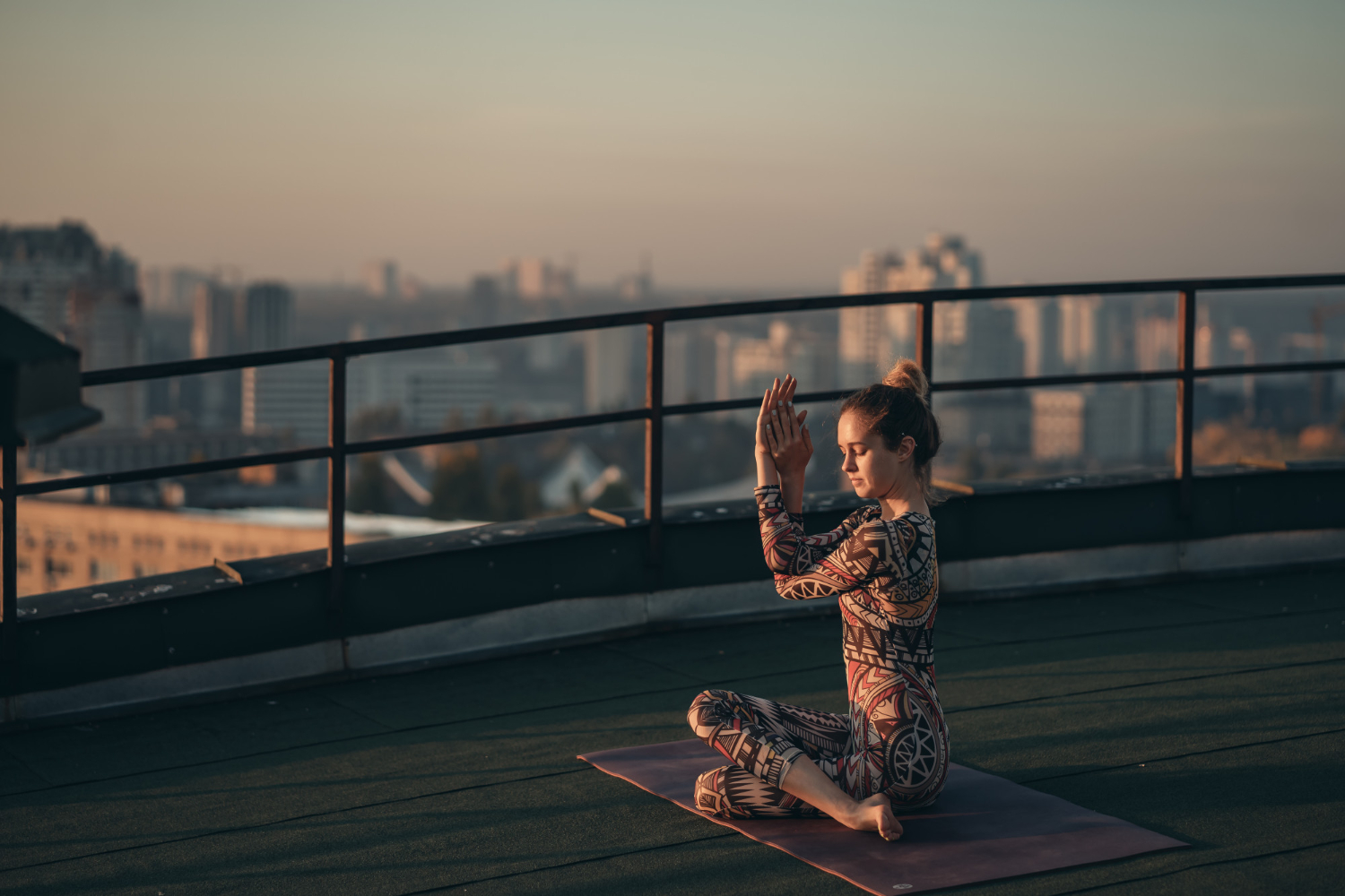 Woman sitting calmly on a yoga mat with hands on heart and belly, practicing grounding yoga for emotional balance and energy protection
